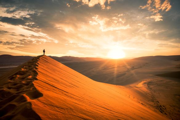 Man watching dramatic sunrise over African dessert